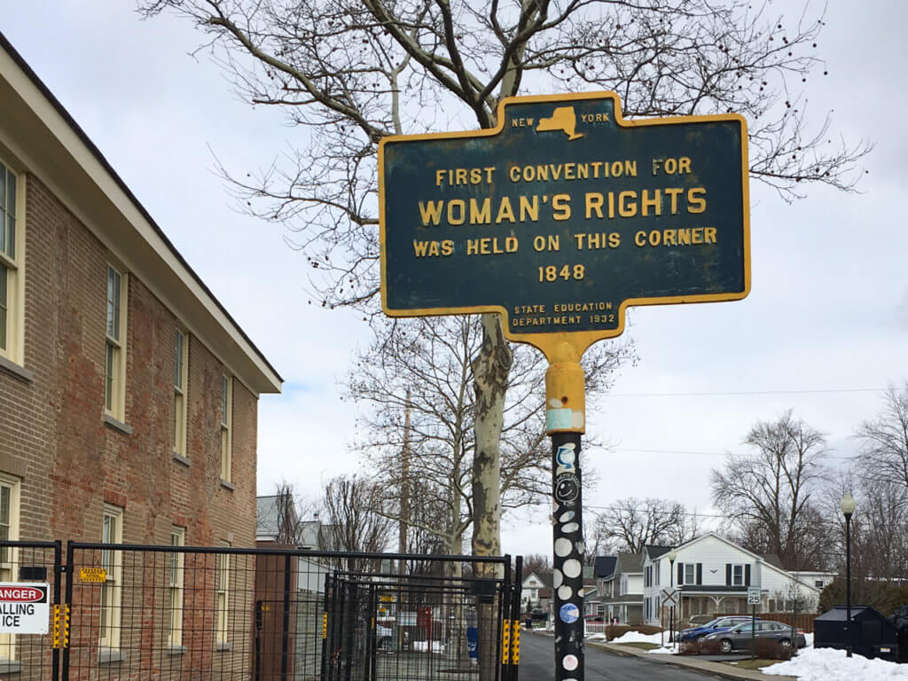 Blue historical marker sign that says, "First Convention for Woman's Rights was held on this corner in 1848."