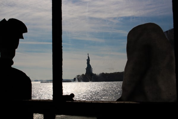 The New York Harbor seen through an iron window frame. The Statue of Liberty is in the distance. 