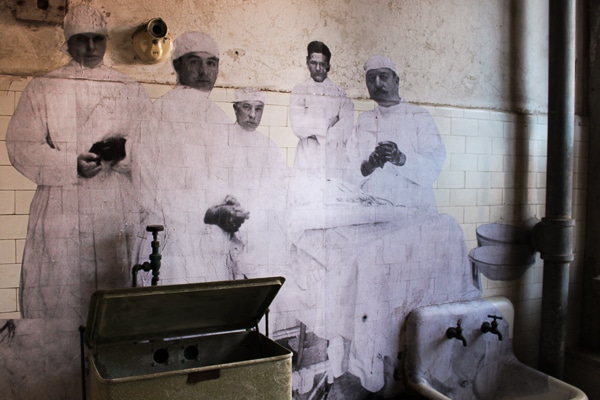 A life-sized black-and-white photo plastered to the wall inside the hospital complex. Photo is of 5 doctors dressed in white scrubs. 