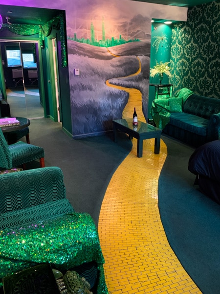 Wizard of Oz-themed motel room. The floor is green carpet with a yellow tiled "brick road" leading into a mural of the Emerald City.