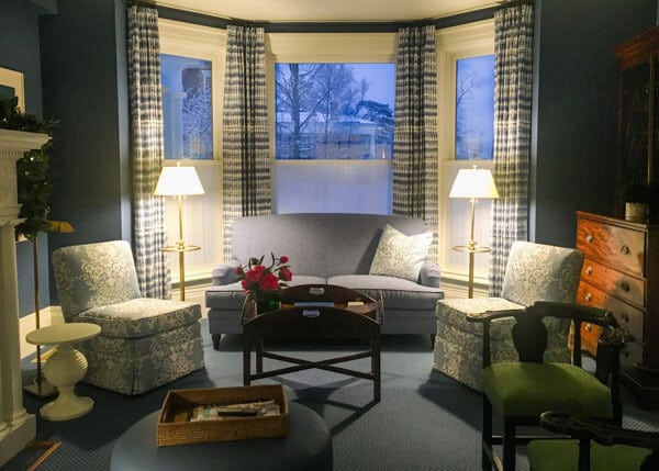 Blue loveseat with blue chairs on either side in front of a bay window in Zabriskie House parlor