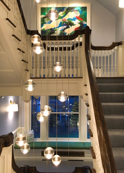 Zabriskie House staircase. Chandelier made of several small globe-shaped hanging lights hang in front of the staircase. 