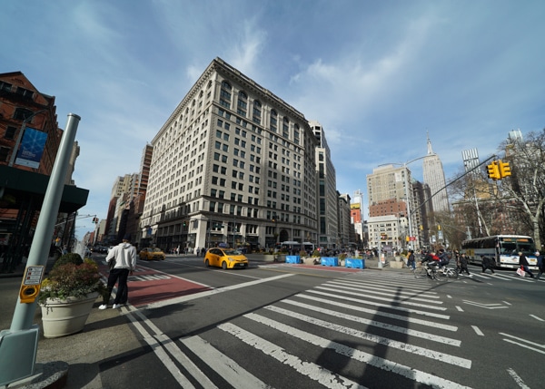 A New York City crosswalk with a six story building in the background.