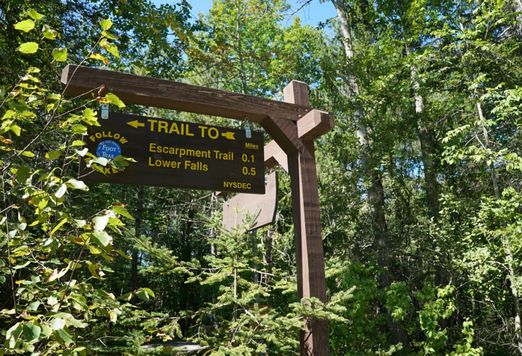 Trail markers on a hiking path that point to Escarpment Trail and Lower Falls.