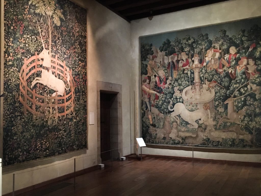 Two large woven tapestries depicting unicorns, hanging on walls at The Met Cloisters in New York City.