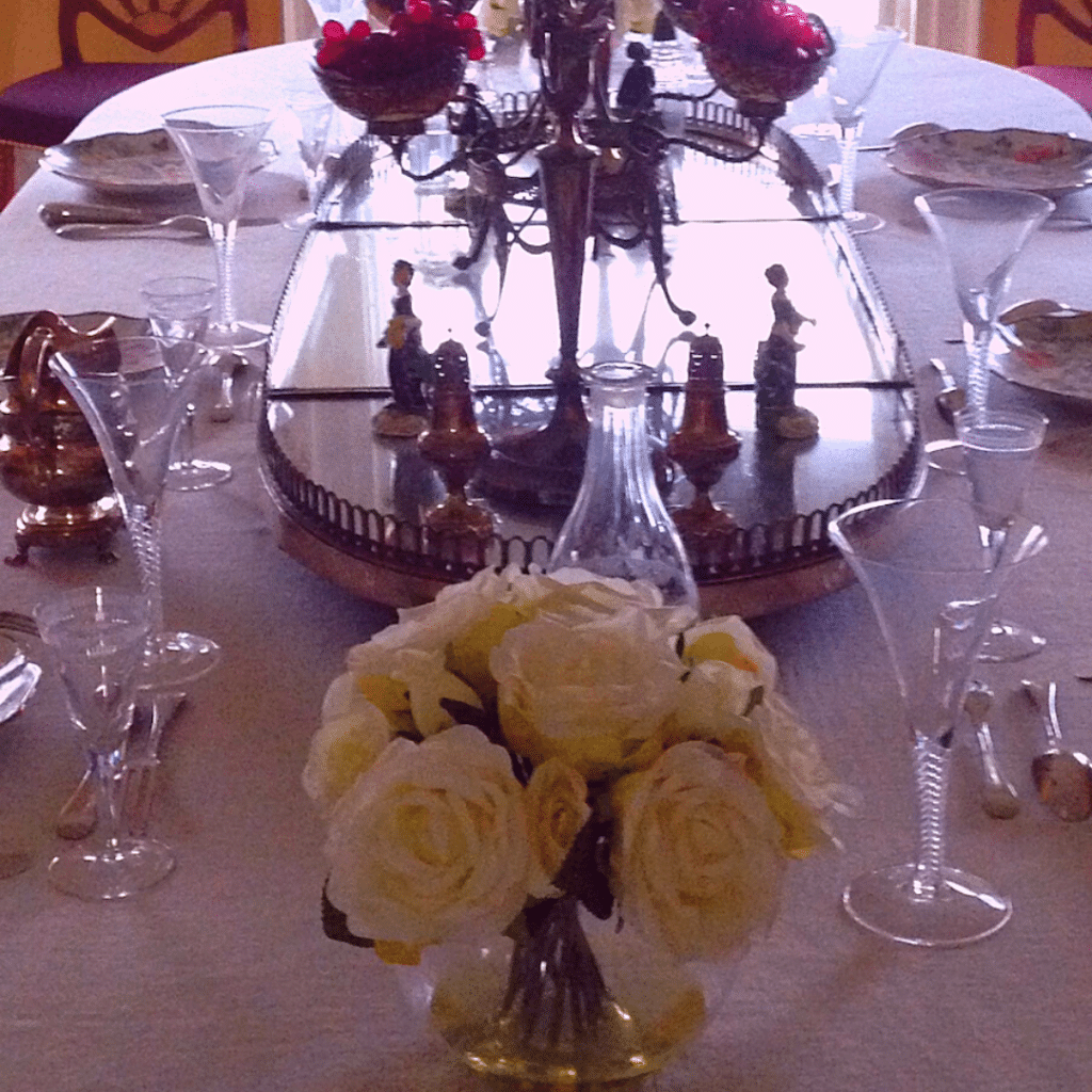 Dining table set with wine glasses and a rose vase centerpiece. Inside Hamilton Grange. 