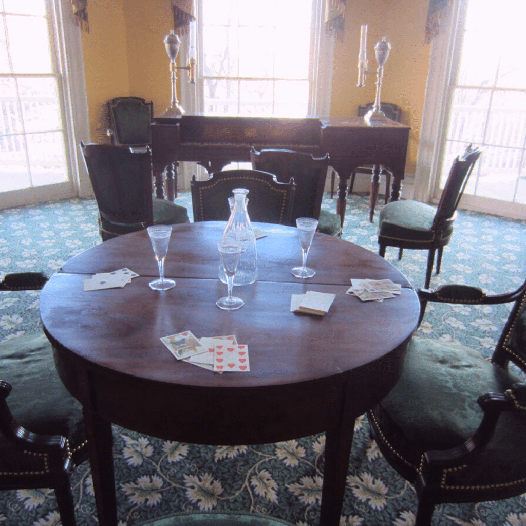 Round wooden table set with wine glasses and decanter. Inside Hamilton Grange. 