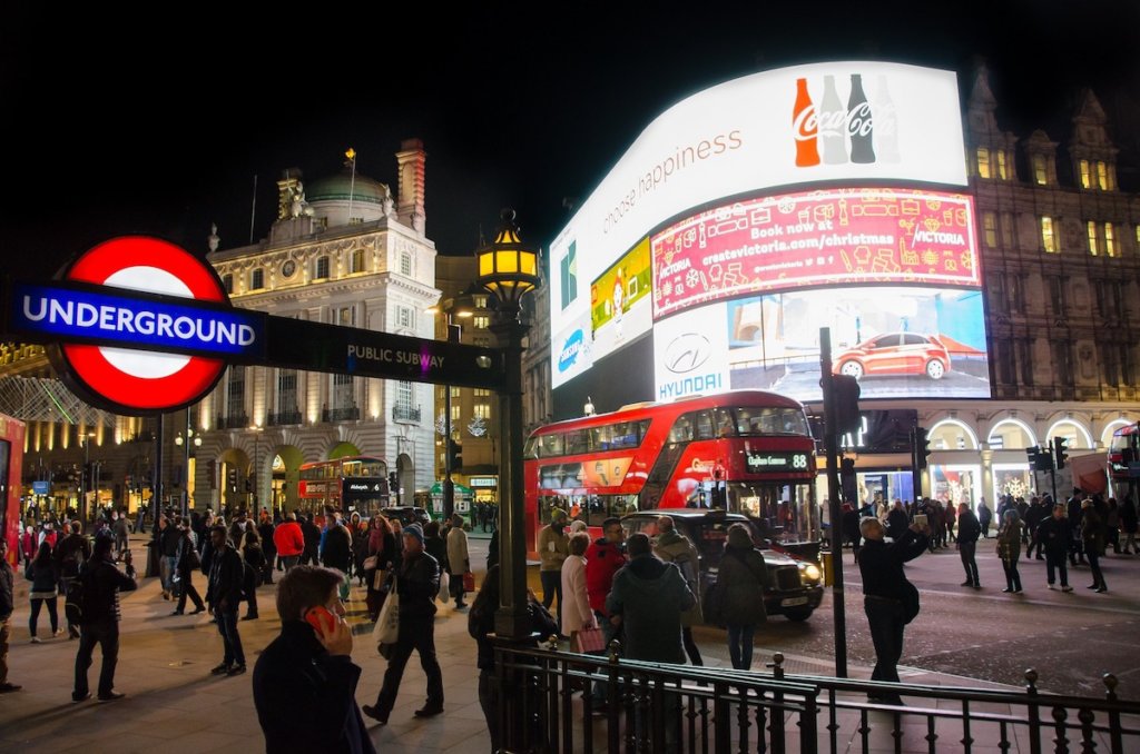 Outside the tube station at Picadilly Circus in London at night.