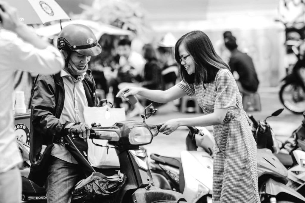 In Ho Chi Minh City, a woman reaches for a package from a man on a motorbike. 