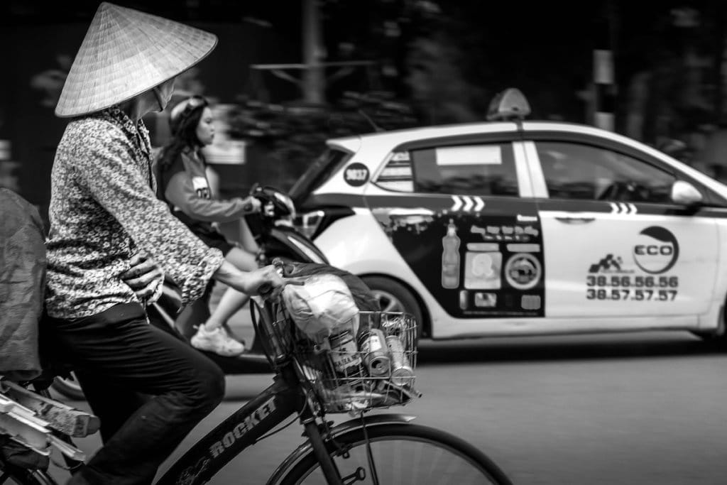 A woman wearing a cone-shaped hat, riding a bicycle in Ho Chi Minh City, Vietnam. 