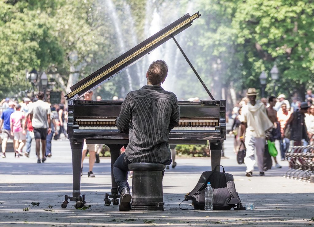 A man plays a piano in the park in New York City.