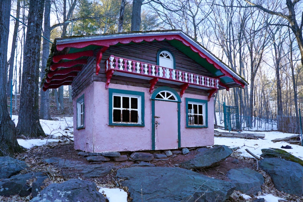 A small concrete animal pen painted pink and trimmed in red, white, and green.