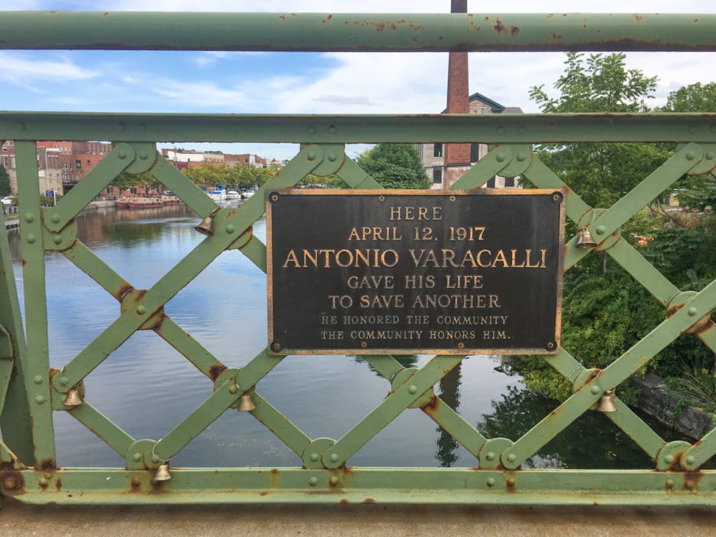 A plaque on the railing of an iron bridge in Seneca Falls, NY that says, "Here, April 12, 1917, Antonio Varacalli Gave His Life To Save Another."