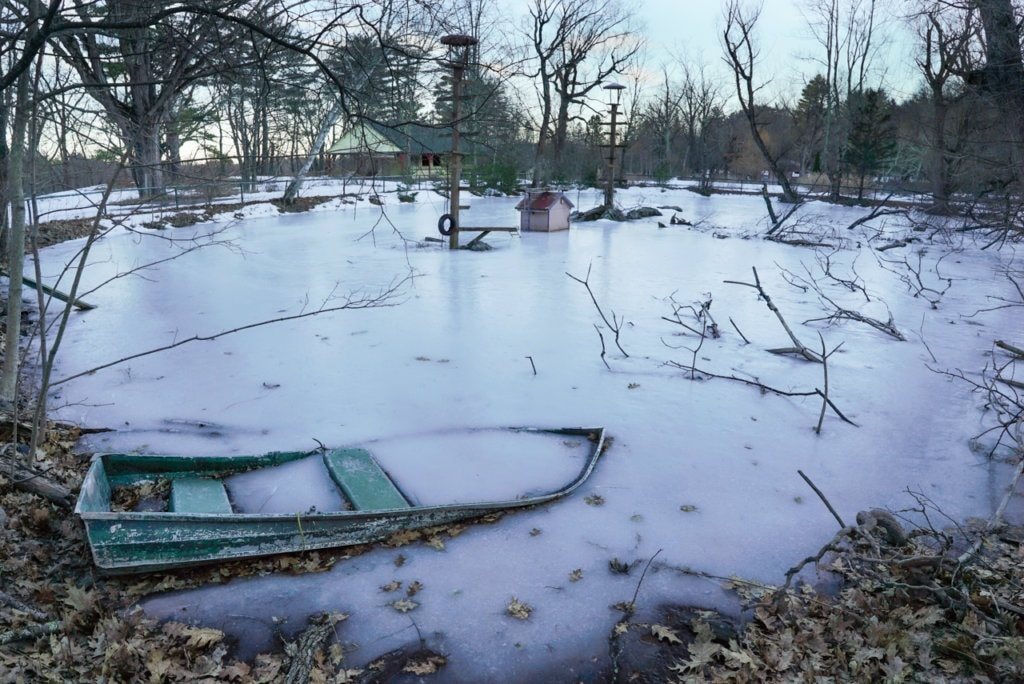 Frozen pond with a rowboat half submerged.