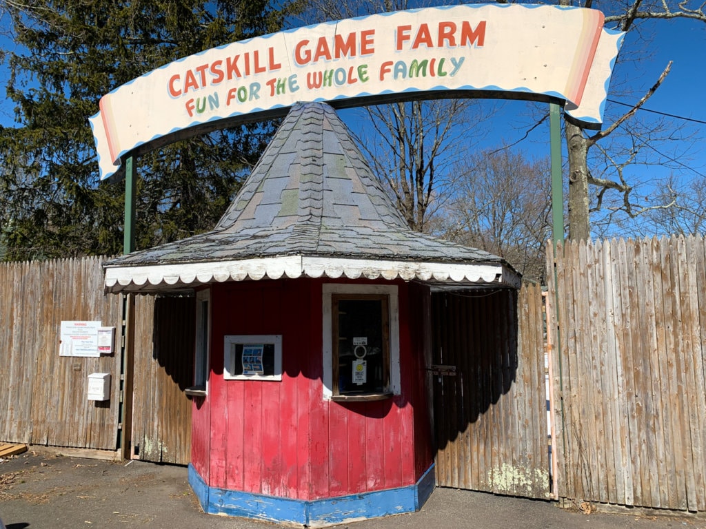 Octagonal red ticket booth. Sign above it says, "Catskill Game Farm: Fun For the Whole Family."