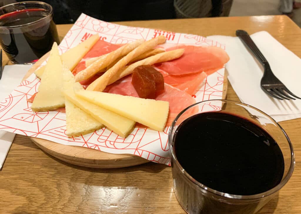 Meat and cheese plate with a glass of wine on either side.