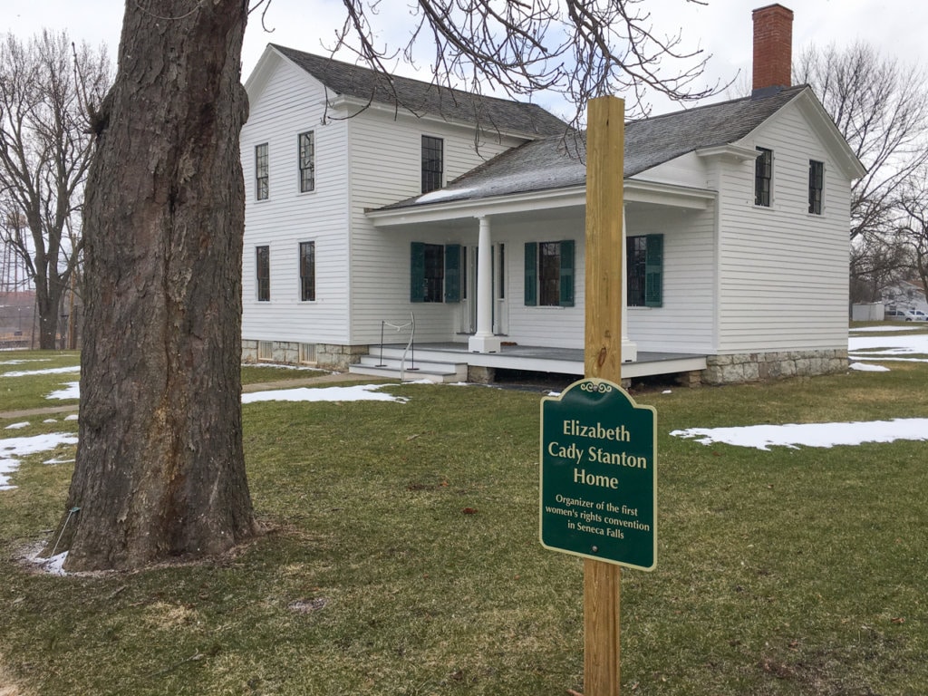 White farmhouse with a sign in front of it marking it as the home of Elizabeth Cady Stanton.