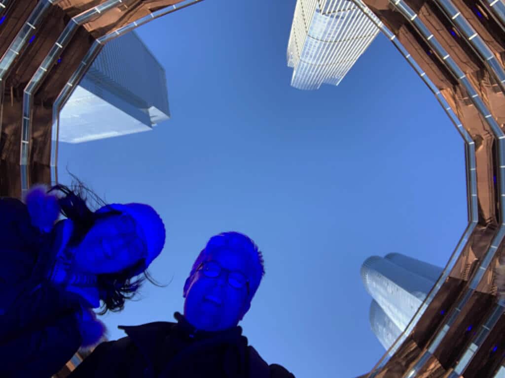 Two people looking down at camera; framed by the Vessel rising above them.
