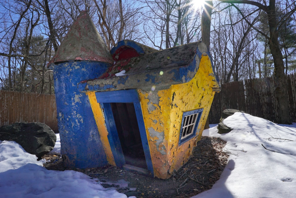 A small concrete animal pen painted blue and yellow. The paint is peeling badly.