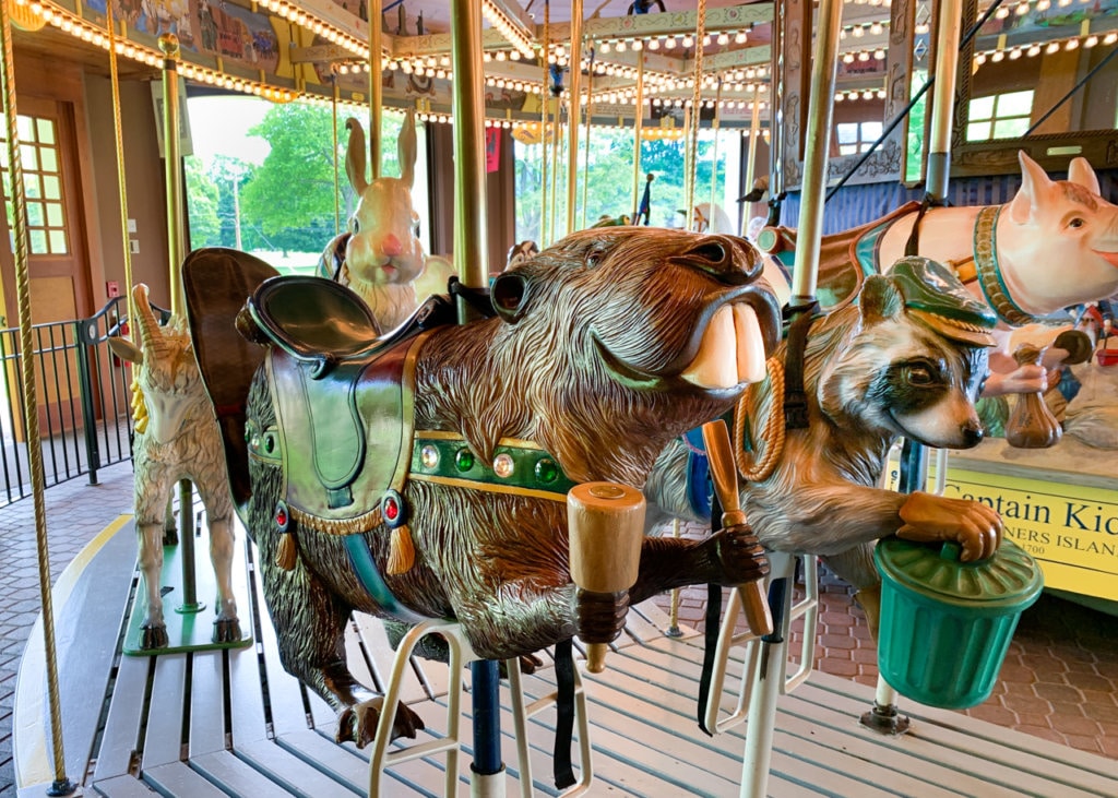 Carousel with animals such as beaver, raccoon, and pig as saddles. 