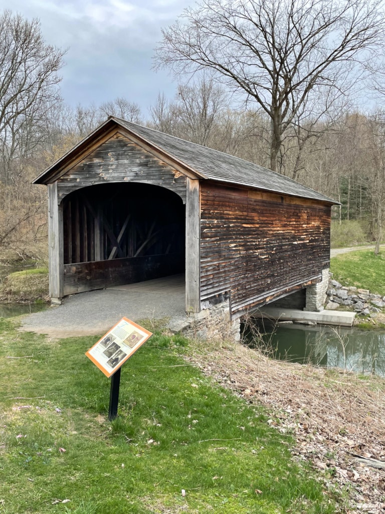 Front view of covered wooden bridge over a creek.
