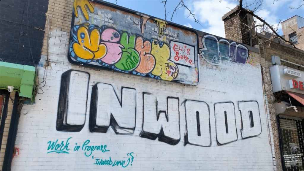 Mural on side of brick building that says, "Inwood" in block letters. Beneath it says, "Work in Progress...Inwood Love."