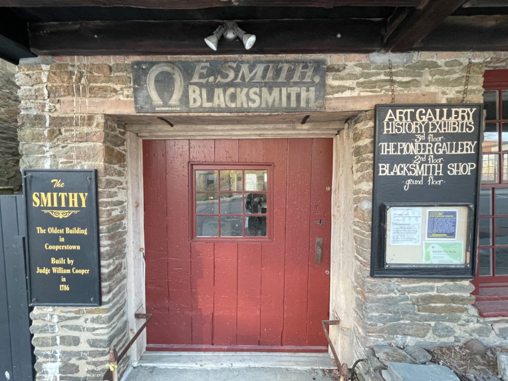 Old brick building with signs indicating it used to be a blacksmith shop and is now an art gallery.