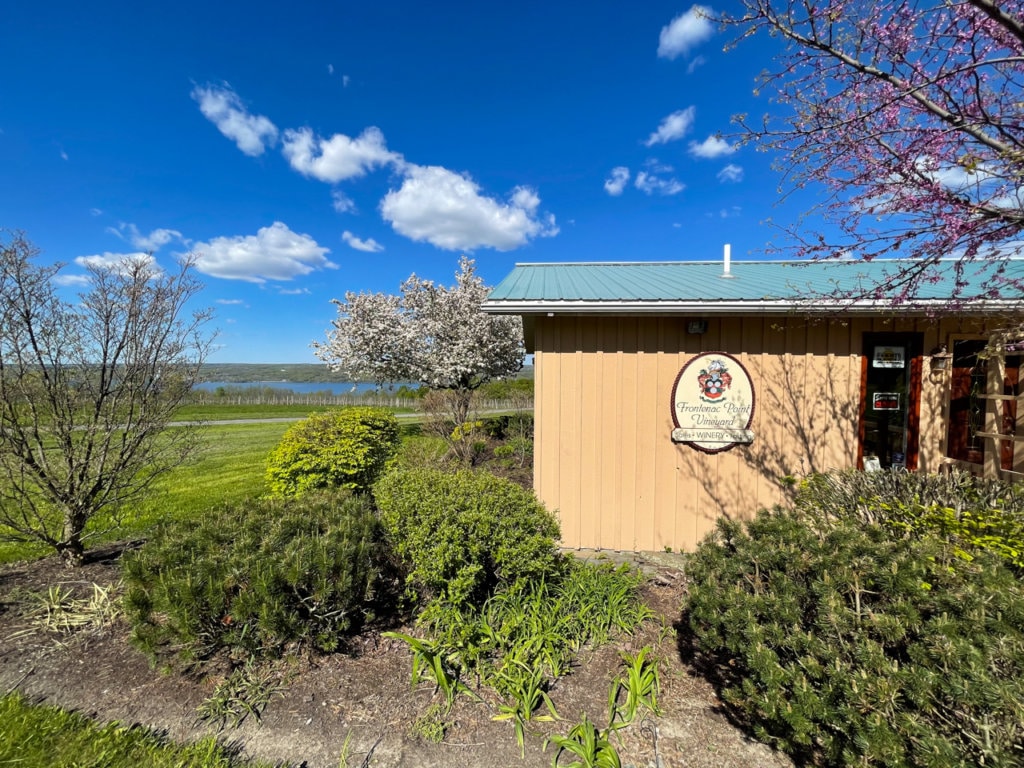 Exterior of a winery tasting room, with Cayuga Lake visible in the background. 