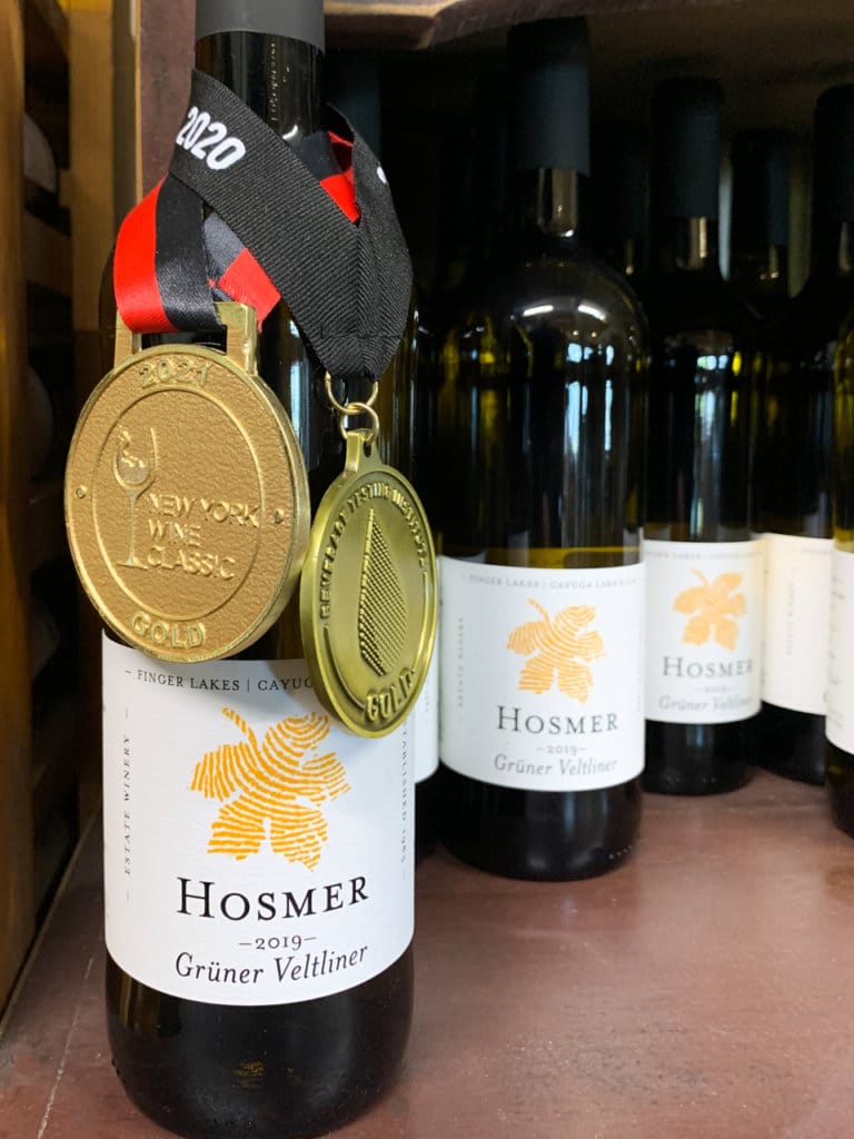 A row of white wine bottles from Hosmer. One bottle is has two gold medals around its neck.