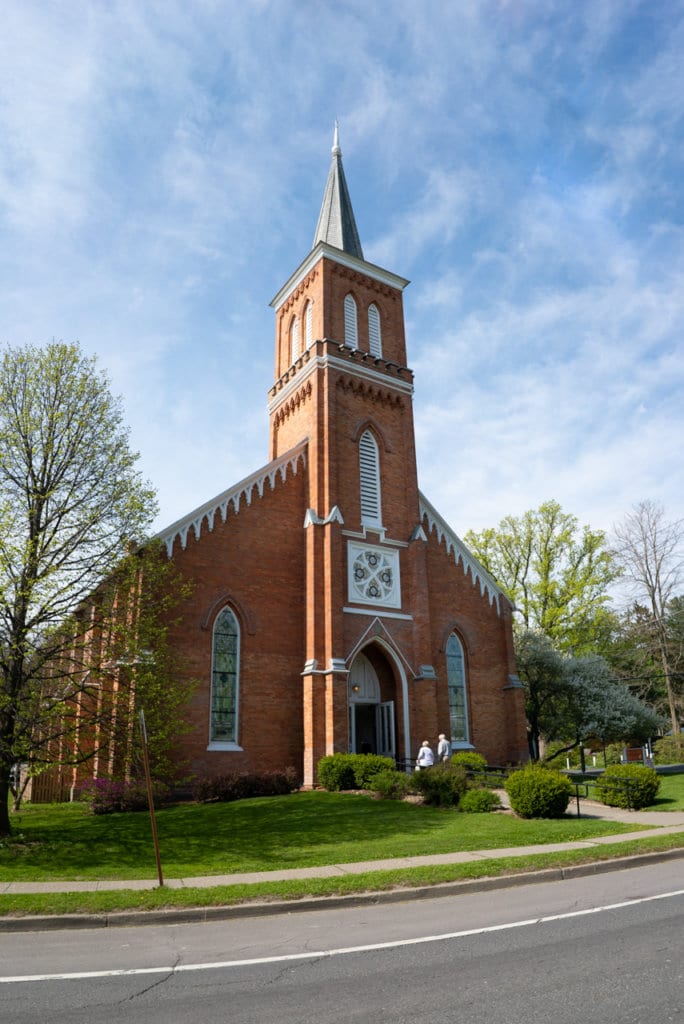 Gothic revival style brick church with a tall steeple. 