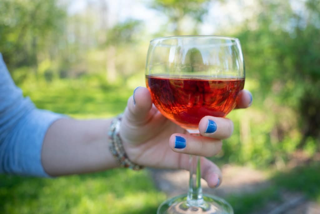Close-up of a woman's hand holding a glass of rose wine. 