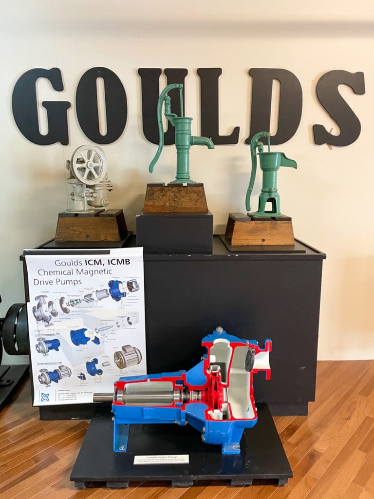 Museum exhibit of Goulds pumps, featuring four old-fashioned pumps and a picture description of how they work.
