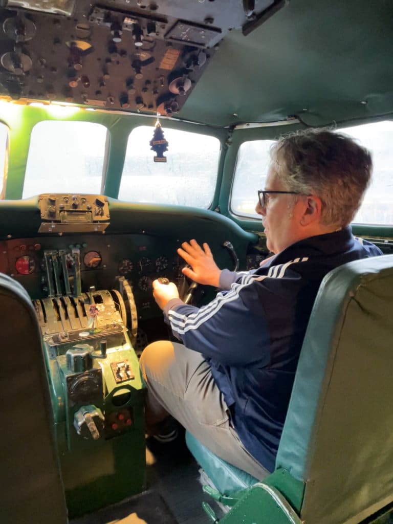 Man sitting in co-pilot seat of a small old-fashioned airplane cockpit. 