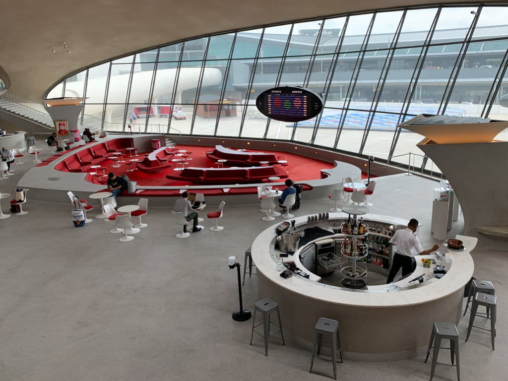 Lounge with bar decorated in red and white inside TWA Hotel. 