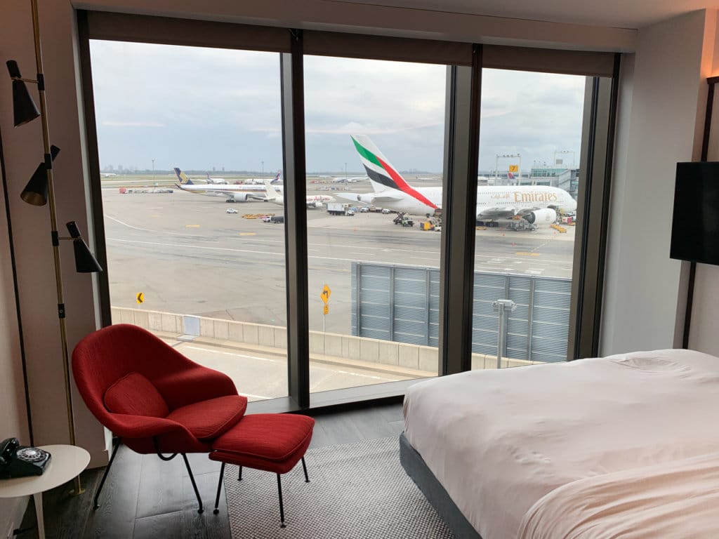Hotel room with floor-to-ceiling window view of airport runway.