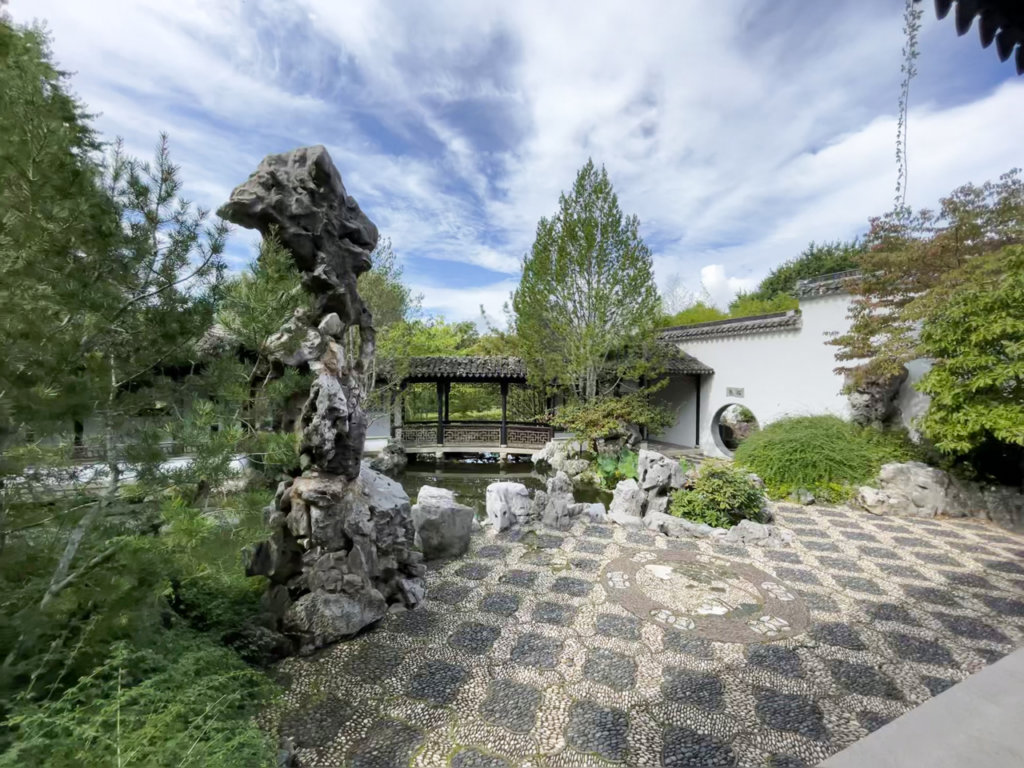 Chinese garden with a tall narrow rock structure. 