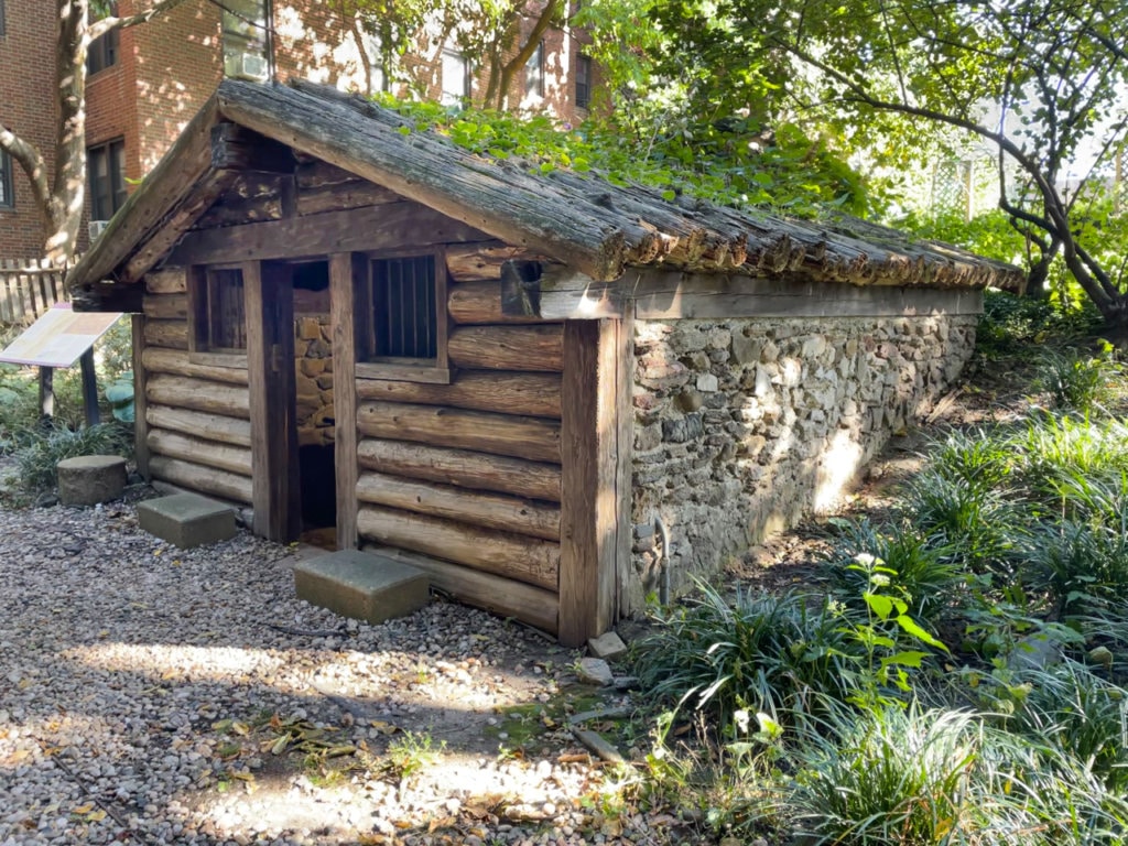 Reconstructed military hut made of logs and stone in the garden at Dyckman Farmhouse Museum.