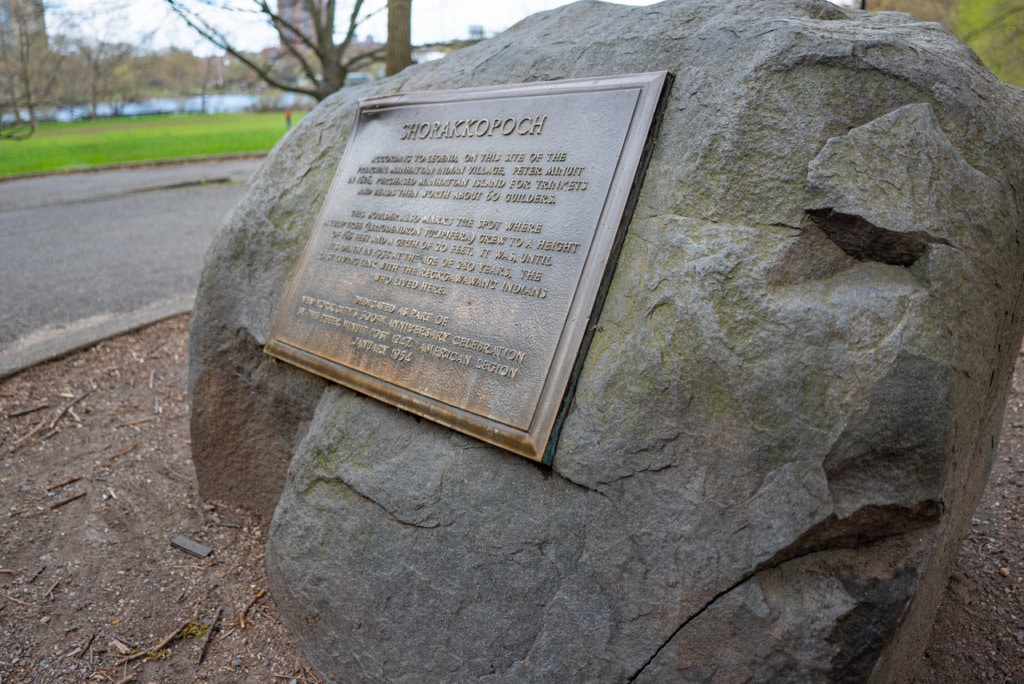 Boulder in Inwood Hill Park with a plaque on it naming it Shorakkapoh Rock. 
