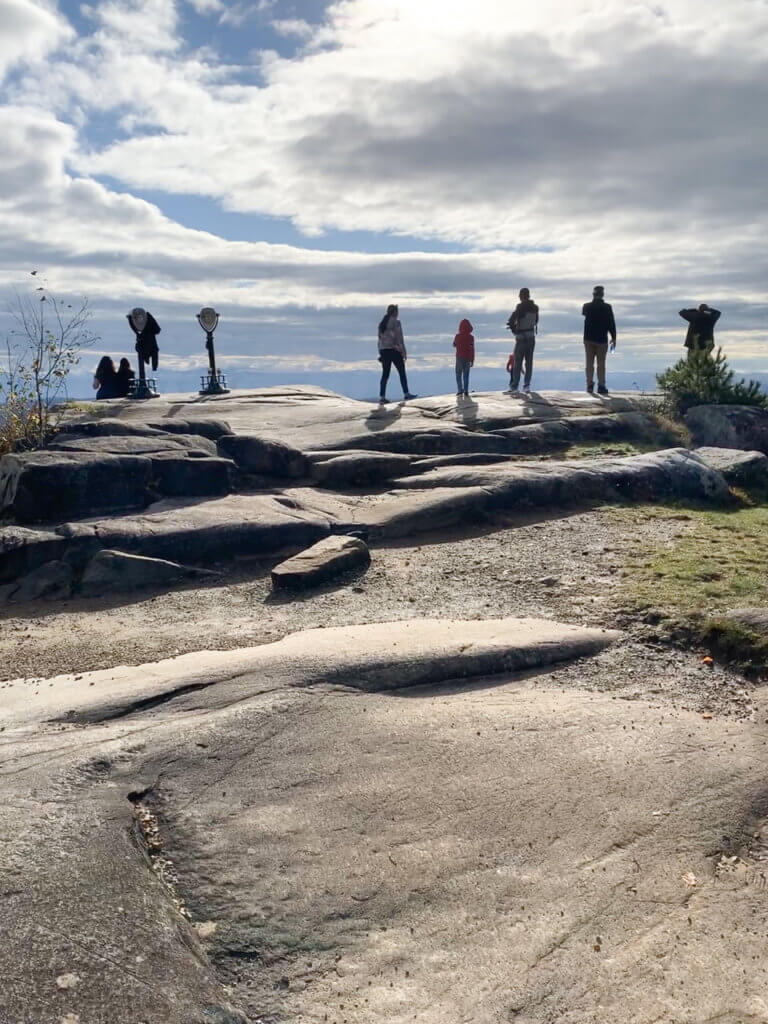 Silhouette of five people standing in a row at the edge of a mountain summit after Lake George hike up Prospect Mountain.