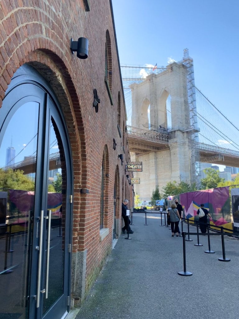 Brick and glass building with the Brooklyn Bridge in the background.
