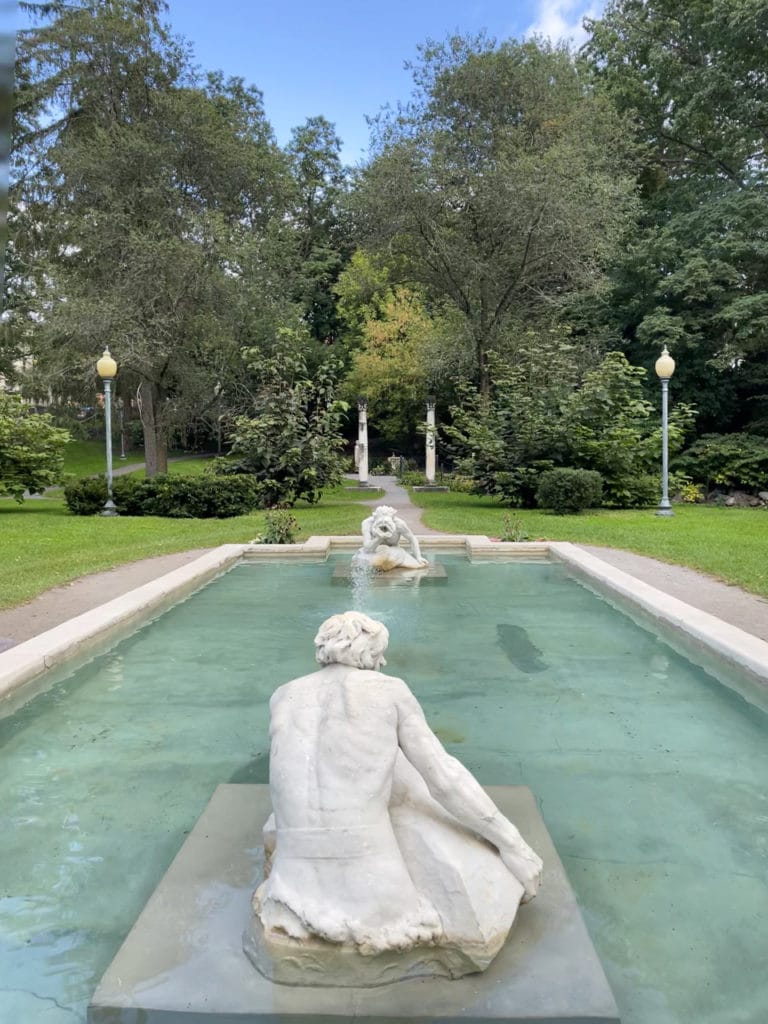 Two marble statues of Tritons on opposite ends of a shallow pool in Congress Park in Saratoga Springs, NY.