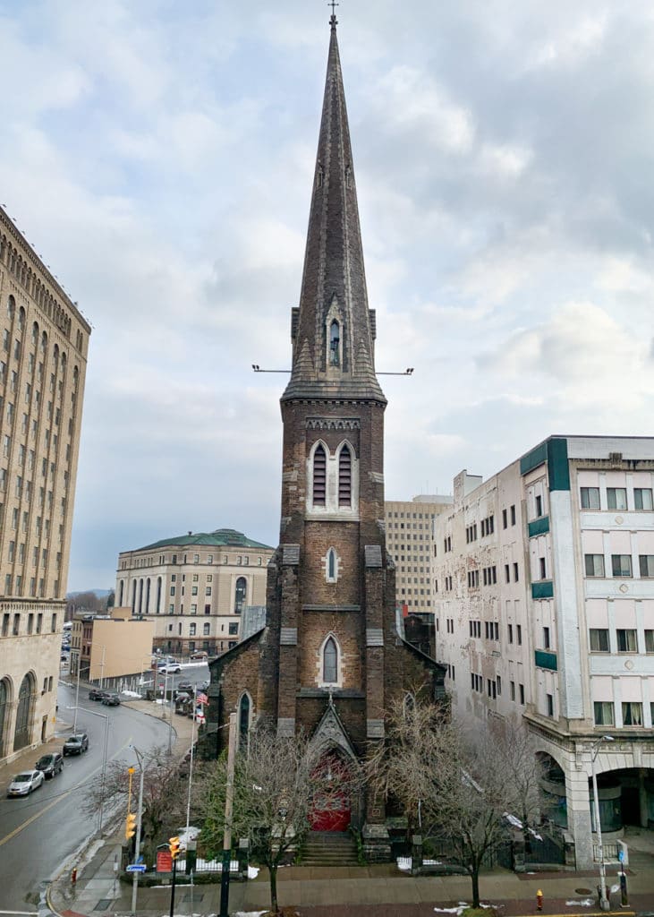 A tall narrow church steeple in downtown Utica, NY.