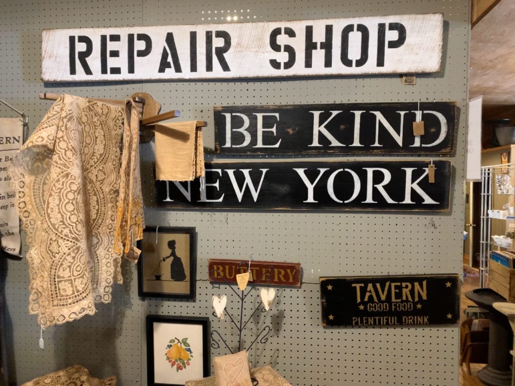 Various antique signs hanging on a wall at an antique vendor mall. 