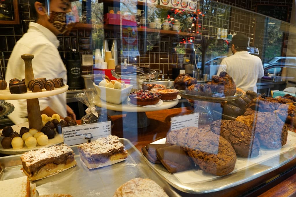Glass display case at a bakery with cookies, tarts, and cakes inside. 