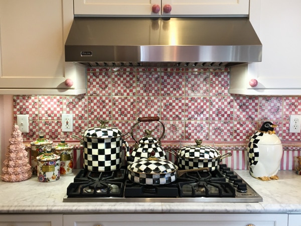 Stovetop with pots and pans in black and white checkered design. Backsplash is pink and white checkered design.