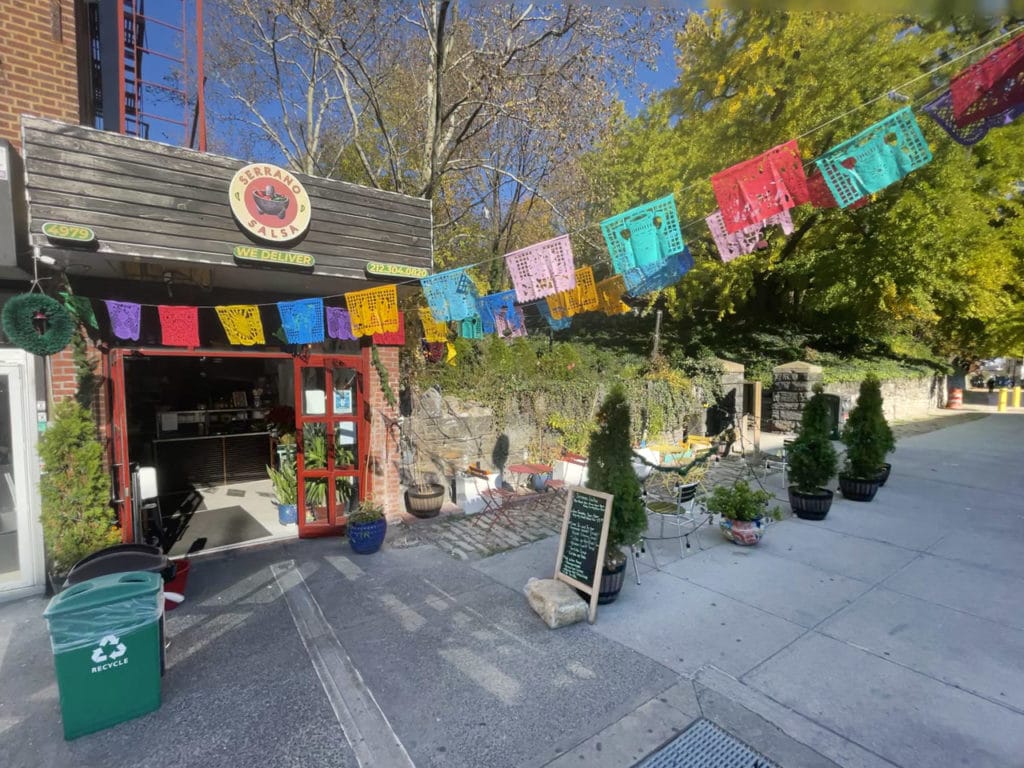 Sidewalk seating decorated with colorful flags at a Mexican restaurant. 
