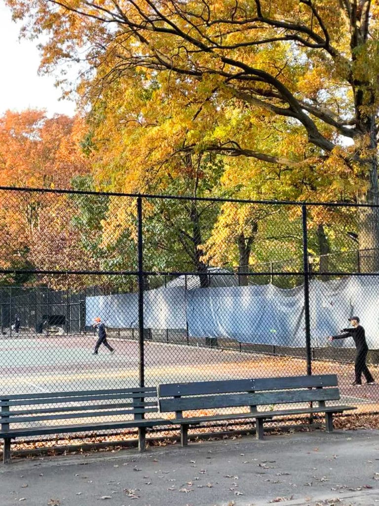People playing tennis court during the fall in Inwood Hill Park, New York City.
