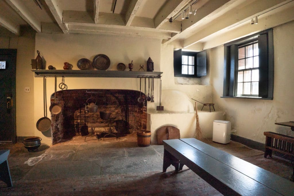 Large brick fireplace in a basement designed to resemble an 18th century kitchen.