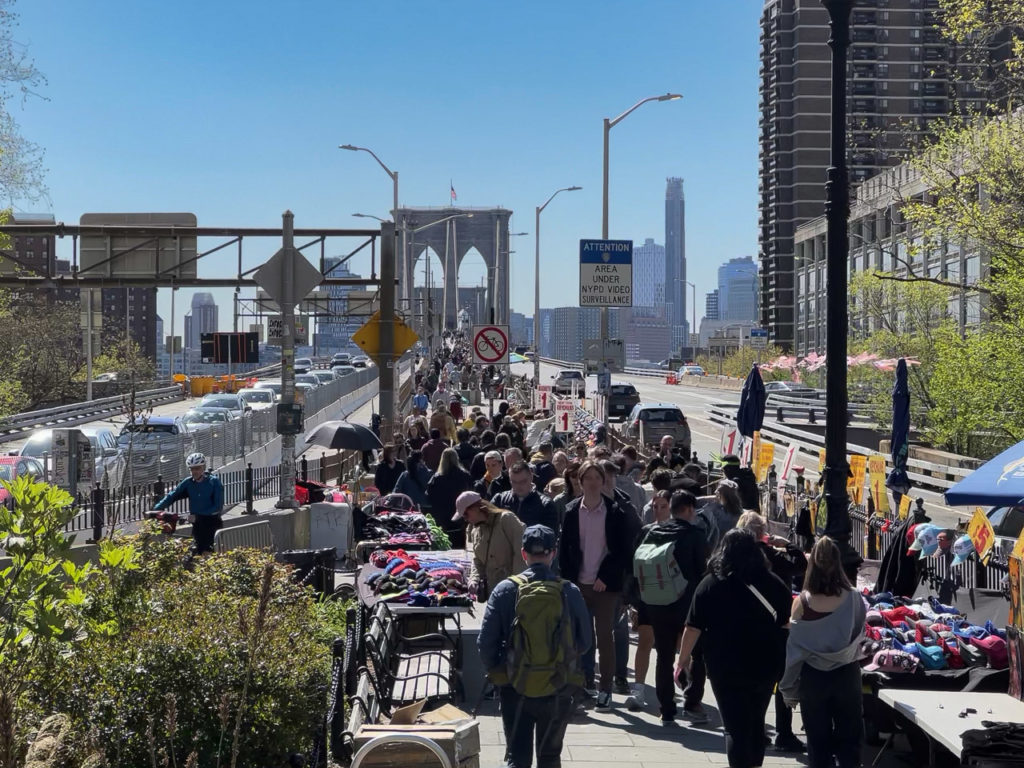 A crowd of people entering the Brooklyn Bridge pedestrian entrance in Manhattan.