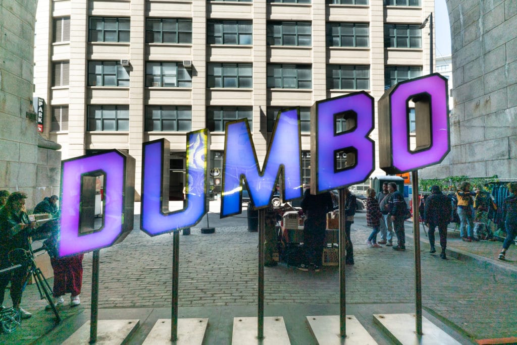 Three dimensional, purple block-letter sign that says DUMBO.